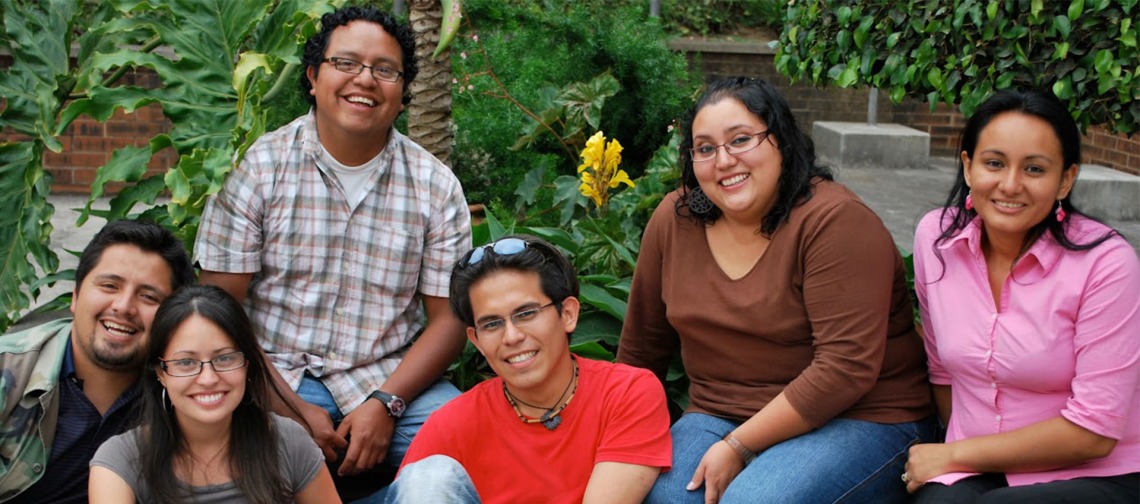 group of hispanic students sitting in a group, outside under a sunny sky