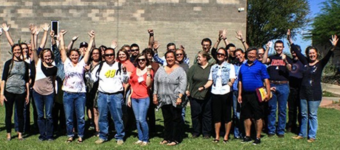 m.ed students group photo, outside under a sunny sky, standing on grass